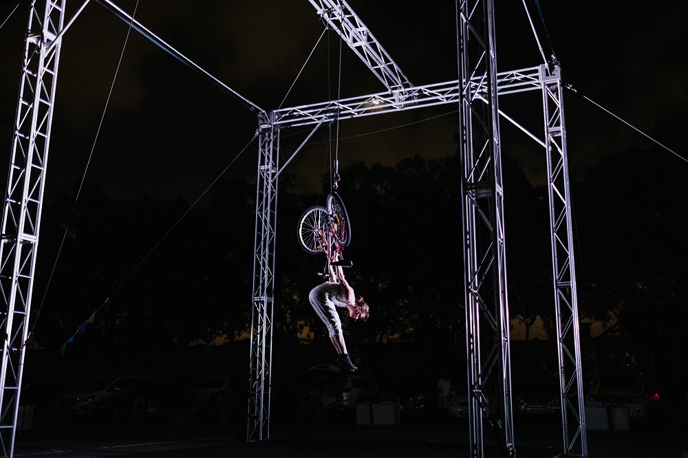 Single performer hanging upside down from scaffold during Rear Vision performance